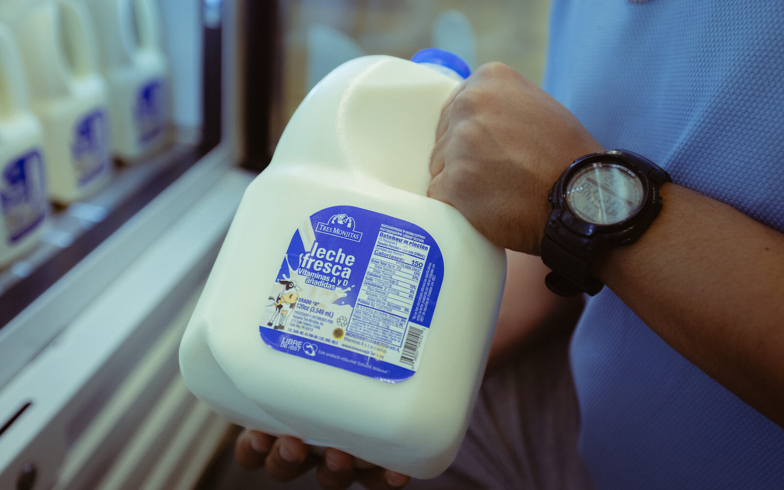 Una persona saca un galón de Leche fresca Tres Monjitas de la nevera